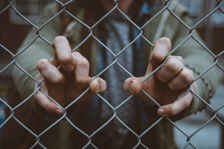 Person holding on to a fence